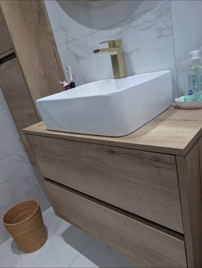 Wood-effect vanity with white basin and brushed brass tap